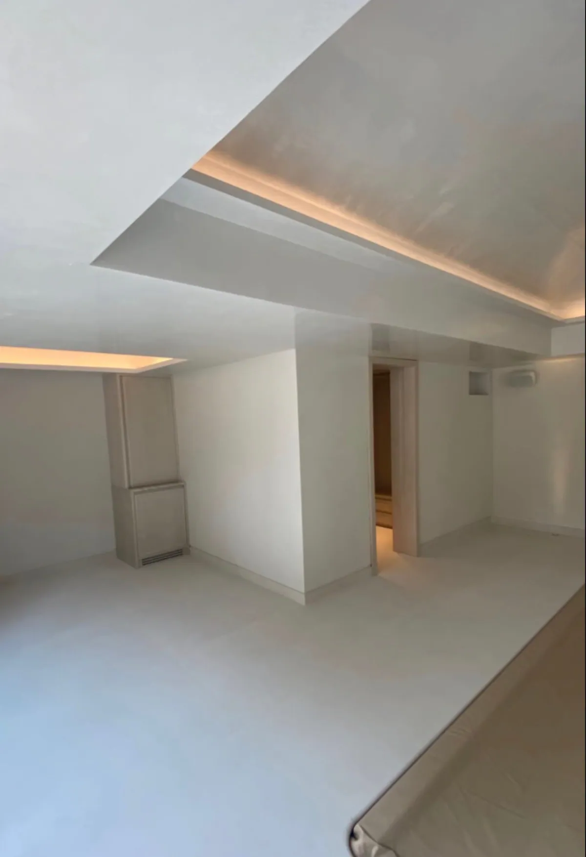 Room with a stepped cove-lit ceiling, a pale floor, a doorway and the edge of a tan pool cover