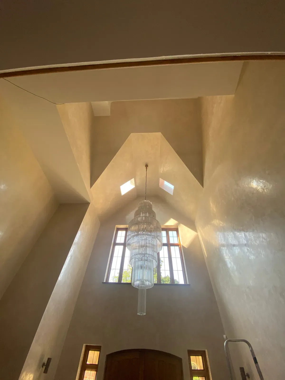 Tall room with a vaulted ceiling, a crystal chandelier and lit windows high on the end wall