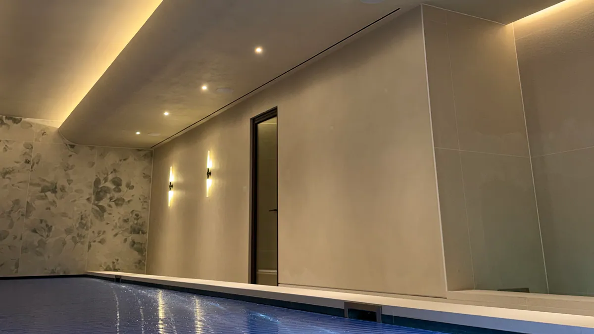 Pool hall with a curved cove-lit ceiling, recessed downlights, wall lights and a covered pool