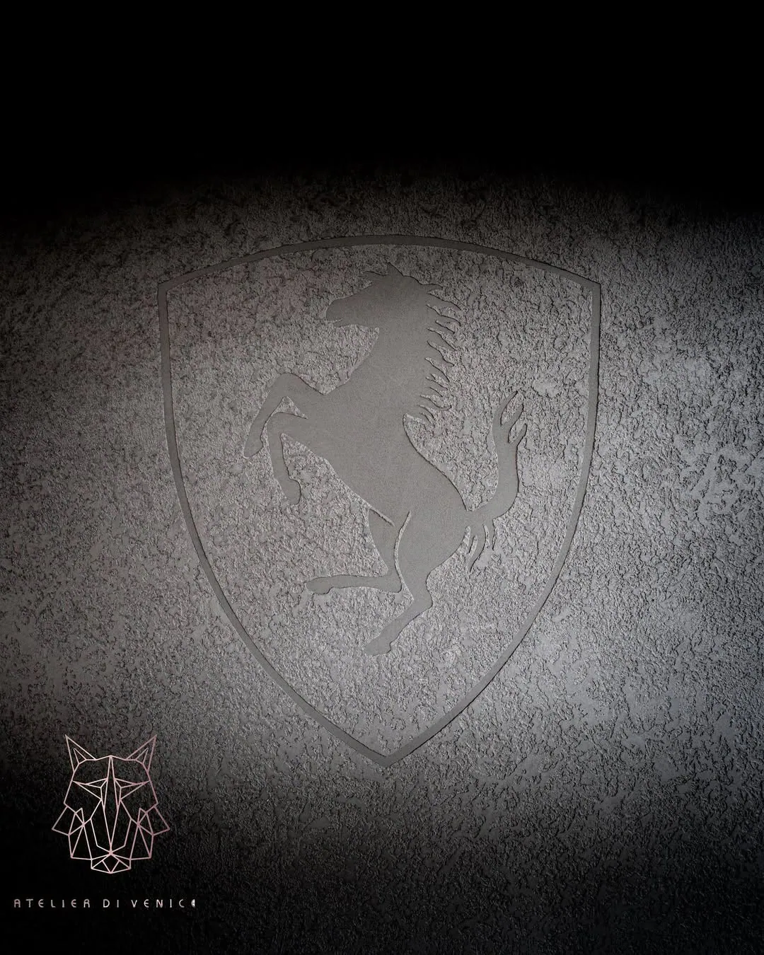 Dark textured wall with a Ferrari shield logo and a small line-drawn logo beneath it